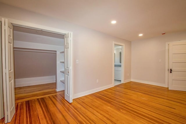 unfurnished bedroom featuring wood-type flooring, ensuite bathroom, and a closet