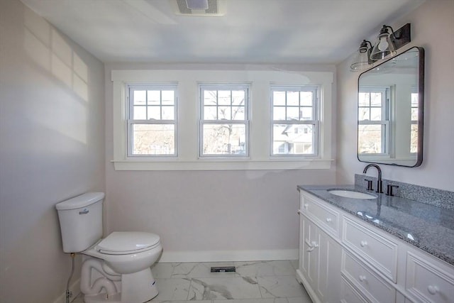 bathroom featuring vanity, a healthy amount of sunlight, and toilet