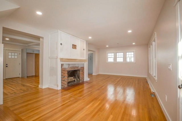 unfurnished living room featuring light hardwood / wood-style floors and a brick fireplace