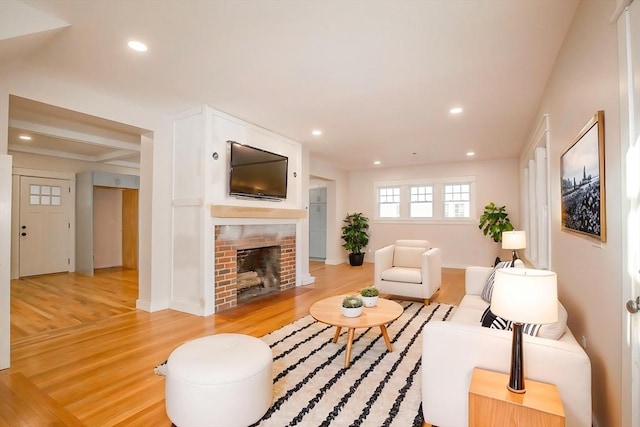 living room featuring light hardwood / wood-style flooring and a brick fireplace