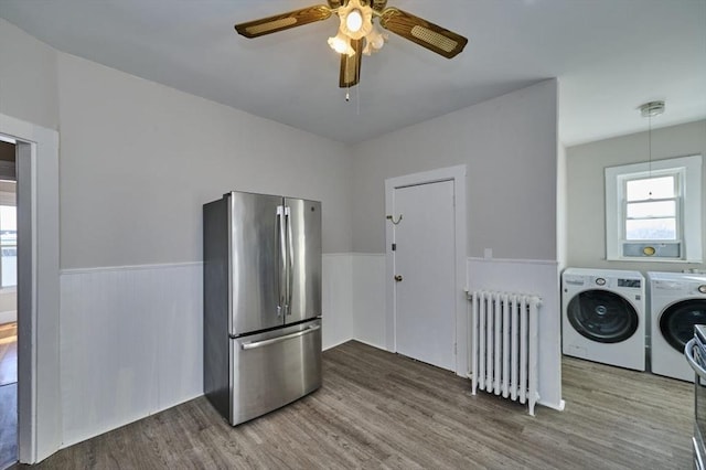 interior space featuring radiator, wood-type flooring, stainless steel fridge, ceiling fan, and washer and clothes dryer