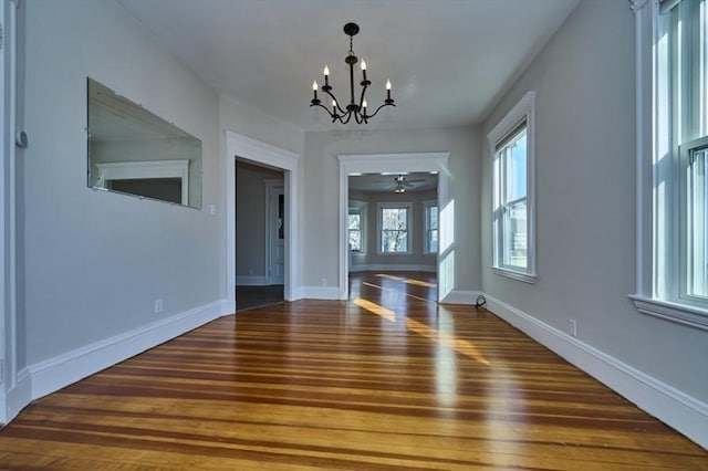 interior space with dark wood-type flooring and ceiling fan with notable chandelier