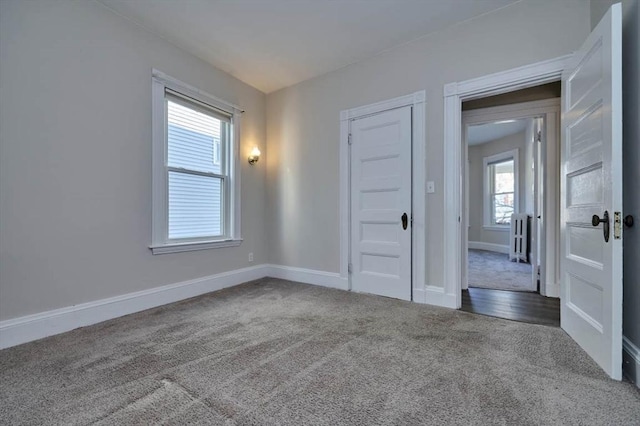 empty room featuring dark colored carpet and plenty of natural light