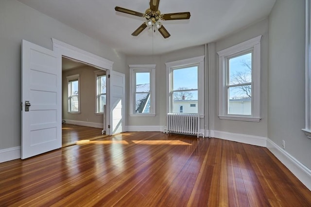 spare room featuring dark hardwood / wood-style floors, radiator heating unit, and ceiling fan