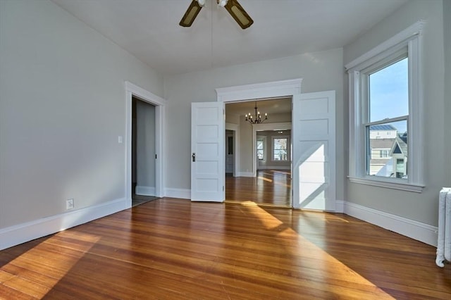 unfurnished room with hardwood / wood-style flooring and ceiling fan with notable chandelier