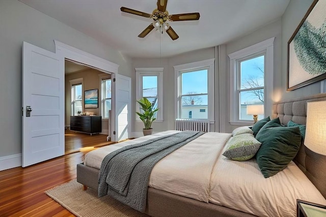 bedroom featuring ceiling fan, radiator heating unit, and dark hardwood / wood-style floors