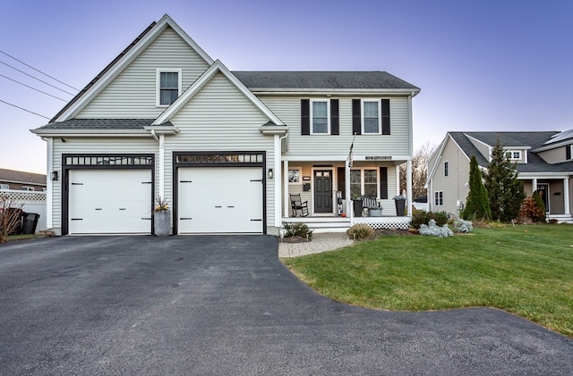 view of front facade with a porch, a garage, and a lawn