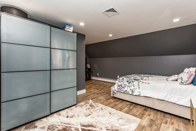 bedroom featuring wood-type flooring, vaulted ceiling, and baseboard heating