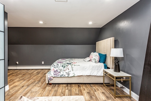 bedroom with lofted ceiling, wood-type flooring, and baseboard heating