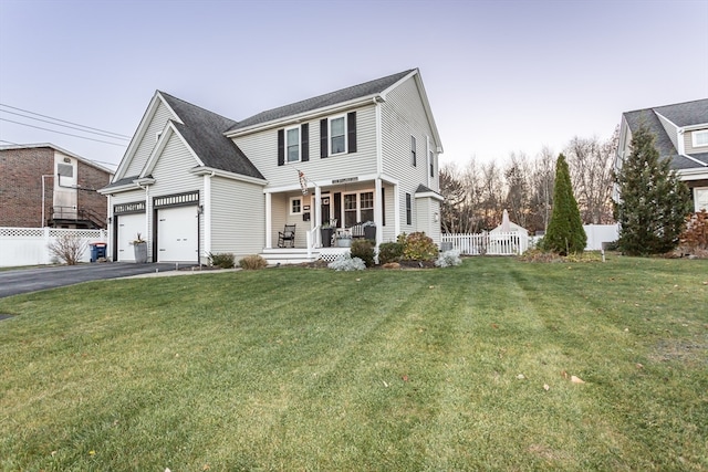 view of front of house featuring a front lawn, covered porch, and a garage