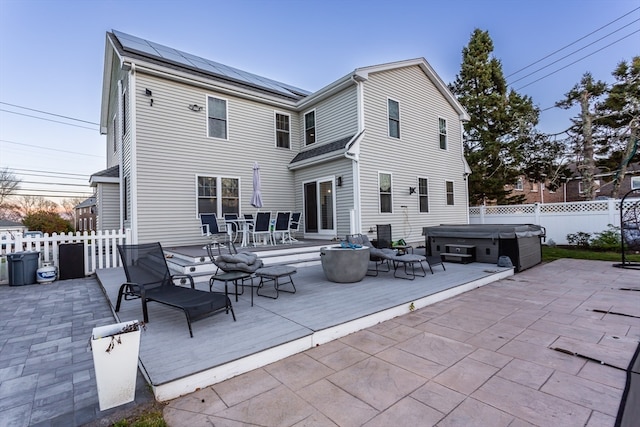 rear view of house featuring a wooden deck, a hot tub, and solar panels