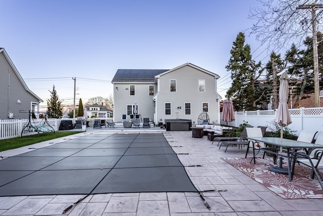 rear view of property with solar panels, a patio, and a hot tub