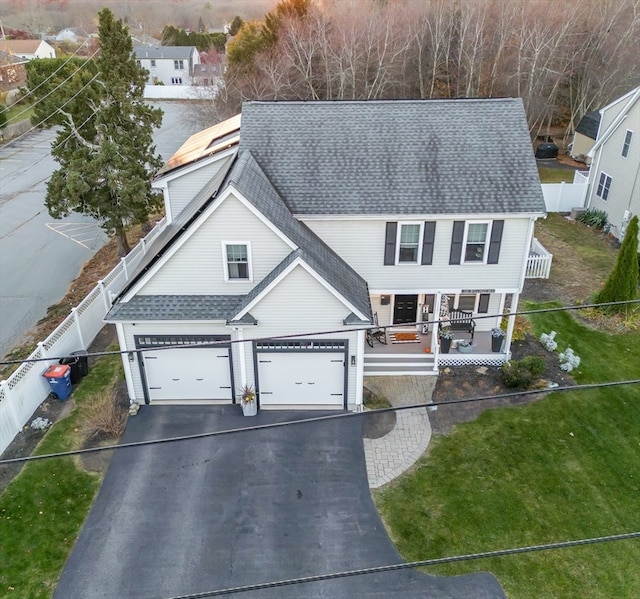 view of front of home featuring a porch, a garage, and a front lawn