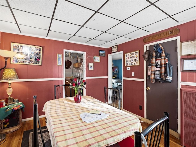 dining area with a paneled ceiling and wood-type flooring