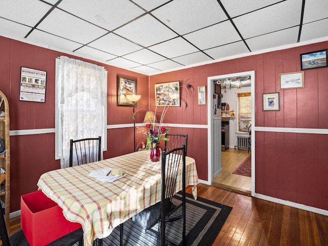 dining space featuring a drop ceiling, radiator, and hardwood / wood-style floors