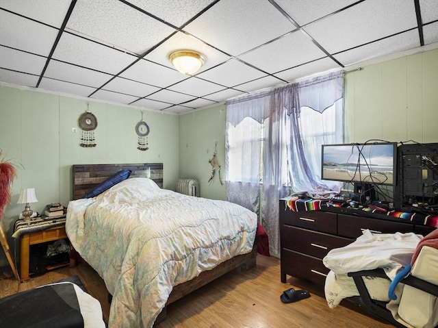 bedroom featuring a drop ceiling, light hardwood / wood-style flooring, and radiator