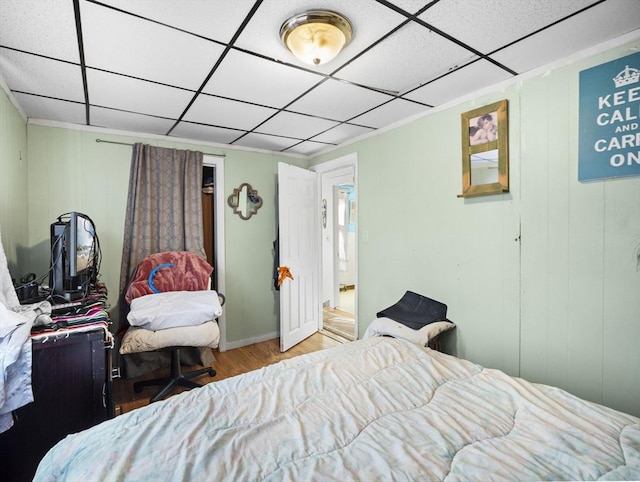 bedroom with a drop ceiling and light wood-type flooring