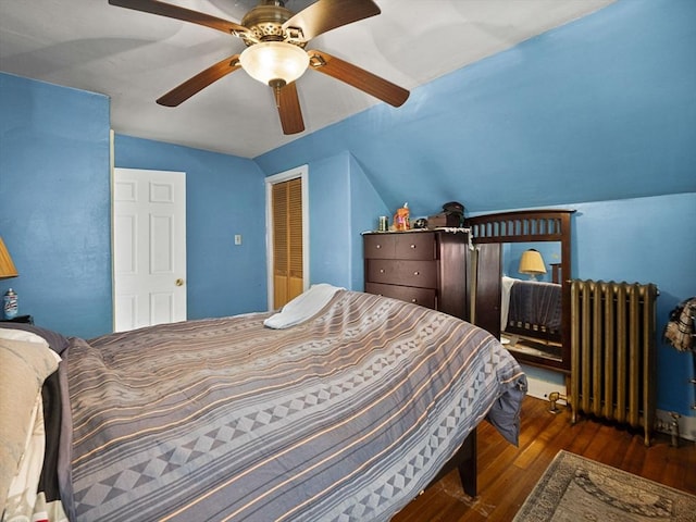 bedroom with a closet, ceiling fan, radiator heating unit, dark hardwood / wood-style floors, and lofted ceiling