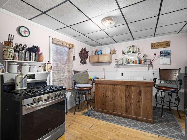 kitchen with a drop ceiling, light hardwood / wood-style flooring, gas stove, and light brown cabinets