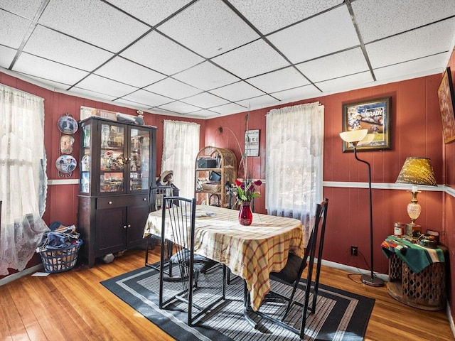 dining space with a paneled ceiling and hardwood / wood-style flooring