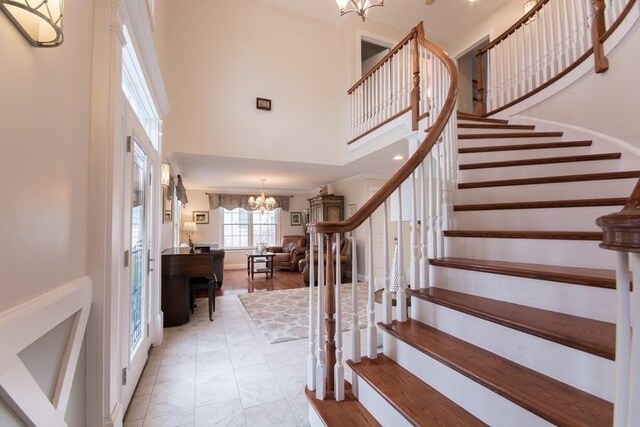 entrance foyer featuring crown molding, a towering ceiling, and an inviting chandelier