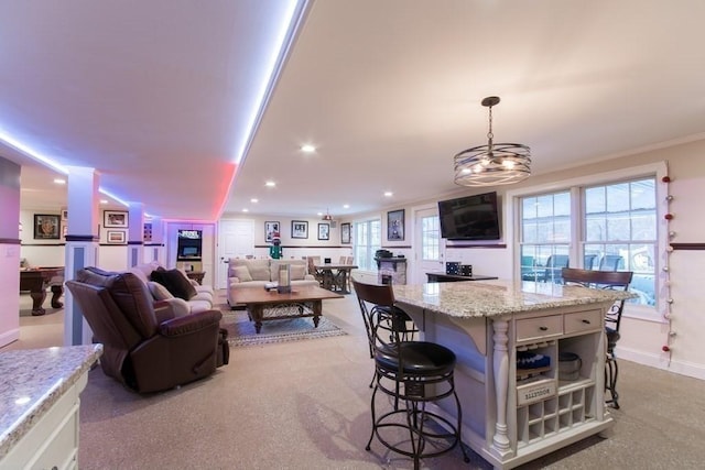 kitchen featuring a kitchen island, white cabinets, a kitchen breakfast bar, hanging light fixtures, and light stone counters