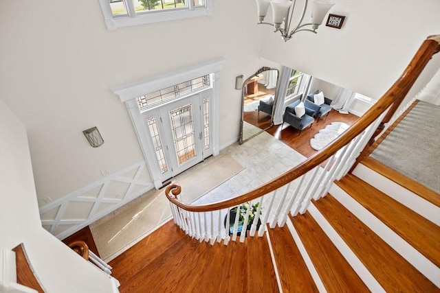 staircase with hardwood / wood-style flooring, a high ceiling, a healthy amount of sunlight, and an inviting chandelier