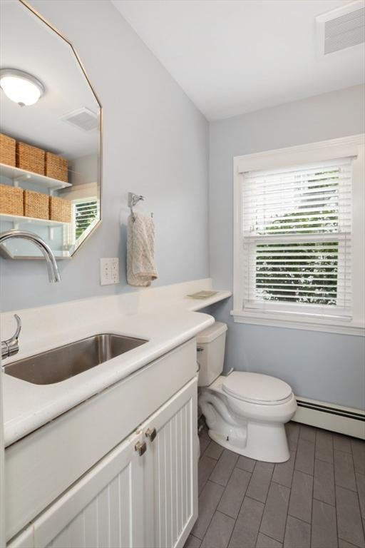 518 Washington St, Winchester, MA 01890 - bathroom with toilet, a baseboard heating unit, vanity, and tile patterned flooring