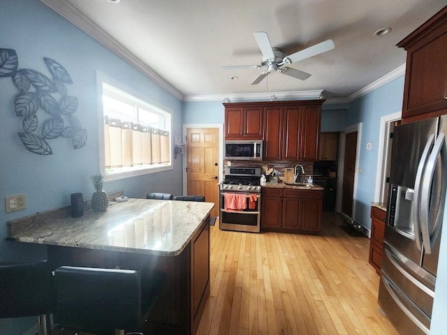 kitchen with light wood-style flooring, stainless steel appliances, a sink, tasteful backsplash, and crown molding