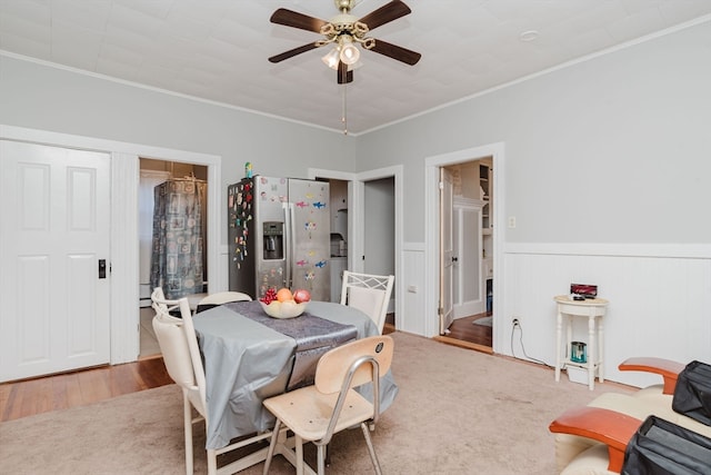 carpeted dining room with crown molding and ceiling fan