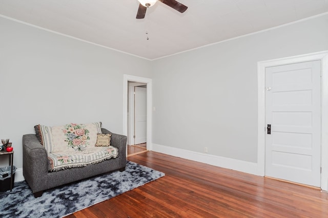 living area featuring wood-type flooring, ornamental molding, and ceiling fan