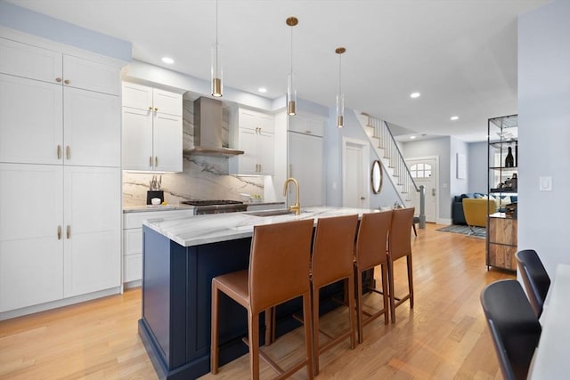 424-430 W 4th St Unit 428, Boston, MA 02127 - kitchen featuring wall chimney exhaust hood, a center island with sink, light wood-type flooring, decorative backsplash, and recessed lighting