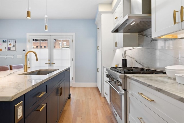 424-430 W 4th St Unit 428, Boston, MA 02127 - kitchen with premium range hood, high end stainless steel range, white cabinetry, light wood-style flooring, and decorative backsplash
