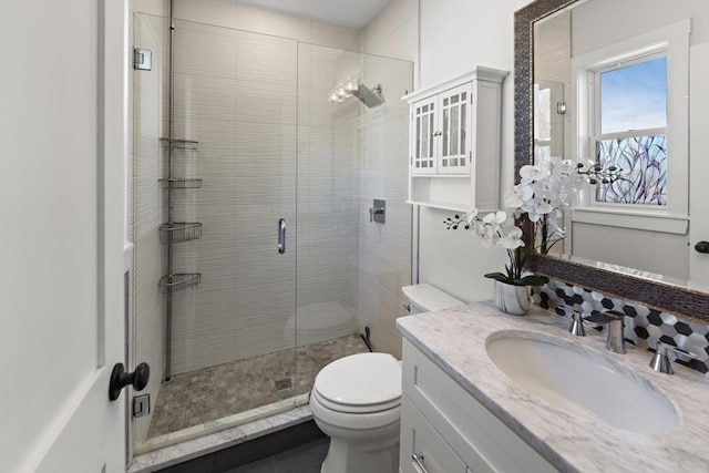 bathroom featuring toilet, an enclosed shower, and vanity