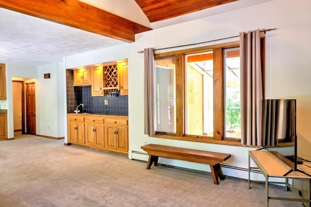 interior space with indoor wet bar, baseboards, and light colored carpet