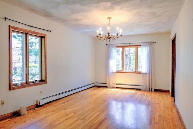 empty room featuring light wood-style flooring, a baseboard heating unit, a notable chandelier, and a healthy amount of sunlight