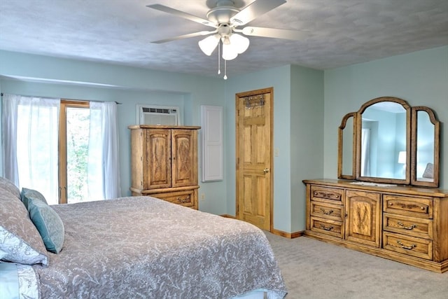 carpeted bedroom with baseboards, a wall unit AC, and a ceiling fan