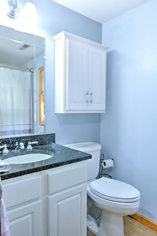 bathroom with vanity, visible vents, wood finished floors, toilet, and a shower with curtain