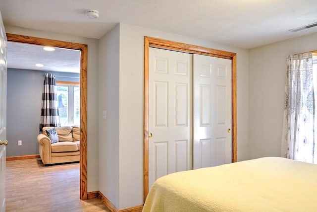 bedroom featuring baseboards, a closet, light wood-type flooring, and visible vents