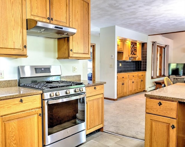 kitchen with decorative backsplash, stainless steel gas range oven, a baseboard radiator, light carpet, and under cabinet range hood