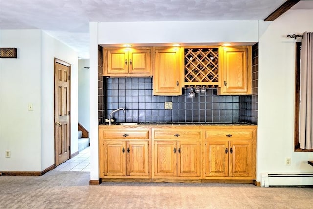 kitchen featuring light carpet, a sink, baseboard heating, tile countertops, and tasteful backsplash