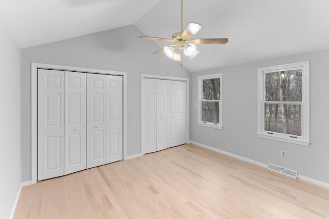 unfurnished bedroom featuring multiple windows, two closets, and light wood-type flooring