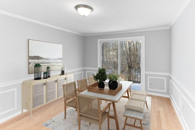 dining space with ornamental molding and light hardwood / wood-style floors