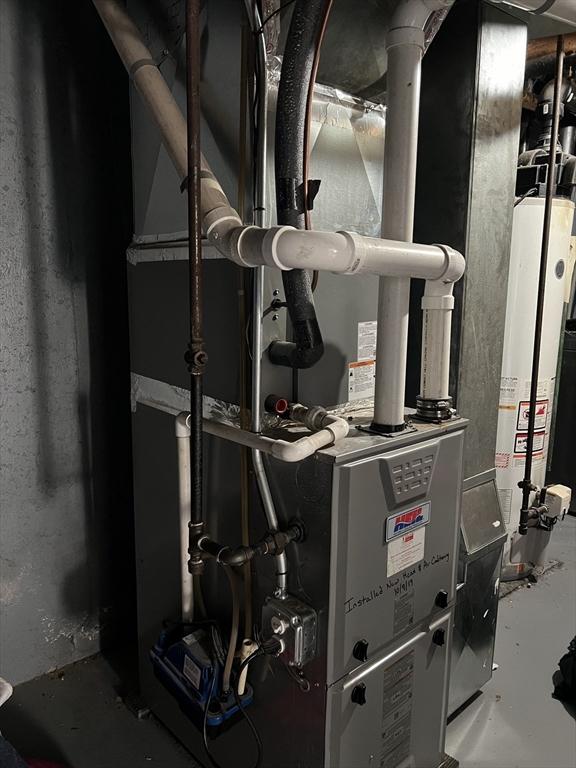 utility room featuring gas water heater and heating unit