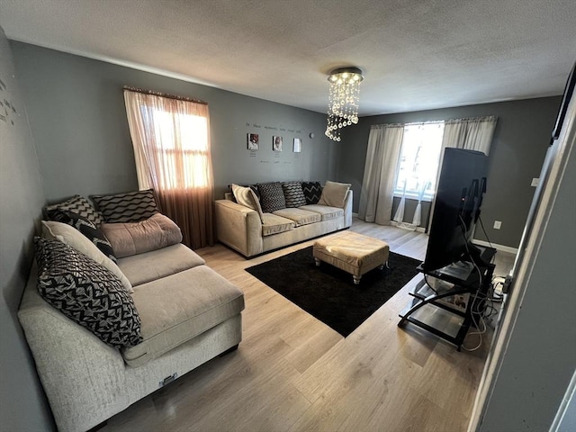 living room with hardwood / wood-style flooring, a healthy amount of sunlight, a chandelier, and a textured ceiling