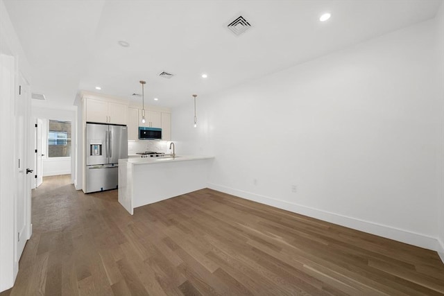 kitchen with pendant lighting, hardwood / wood-style flooring, white cabinetry, kitchen peninsula, and stainless steel appliances