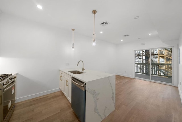 kitchen with light stone countertops, appliances with stainless steel finishes, sink, white cabinets, and hanging light fixtures