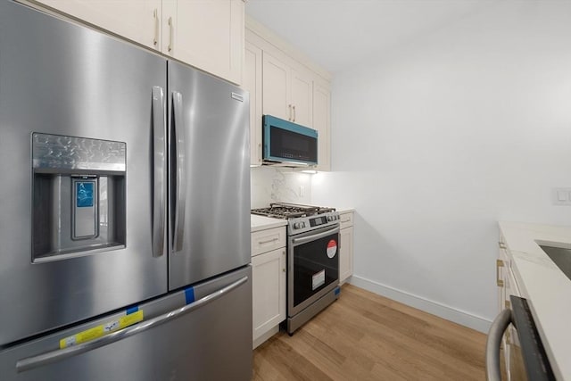 kitchen with white cabinetry, light stone countertops, stainless steel appliances, light hardwood / wood-style flooring, and backsplash