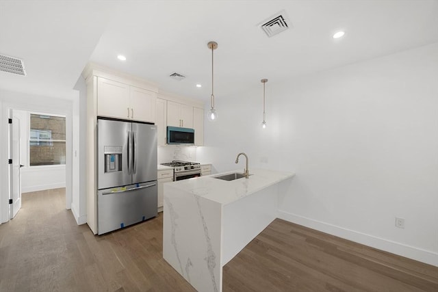 kitchen with pendant lighting, white cabinets, sink, light stone counters, and stainless steel appliances