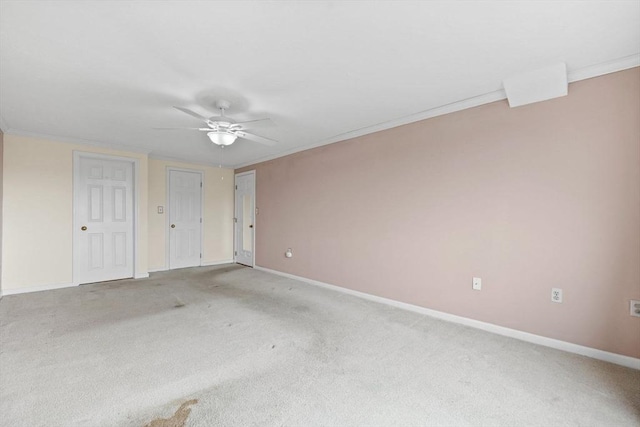 unfurnished bedroom featuring light colored carpet, baseboards, ceiling fan, and ornamental molding
